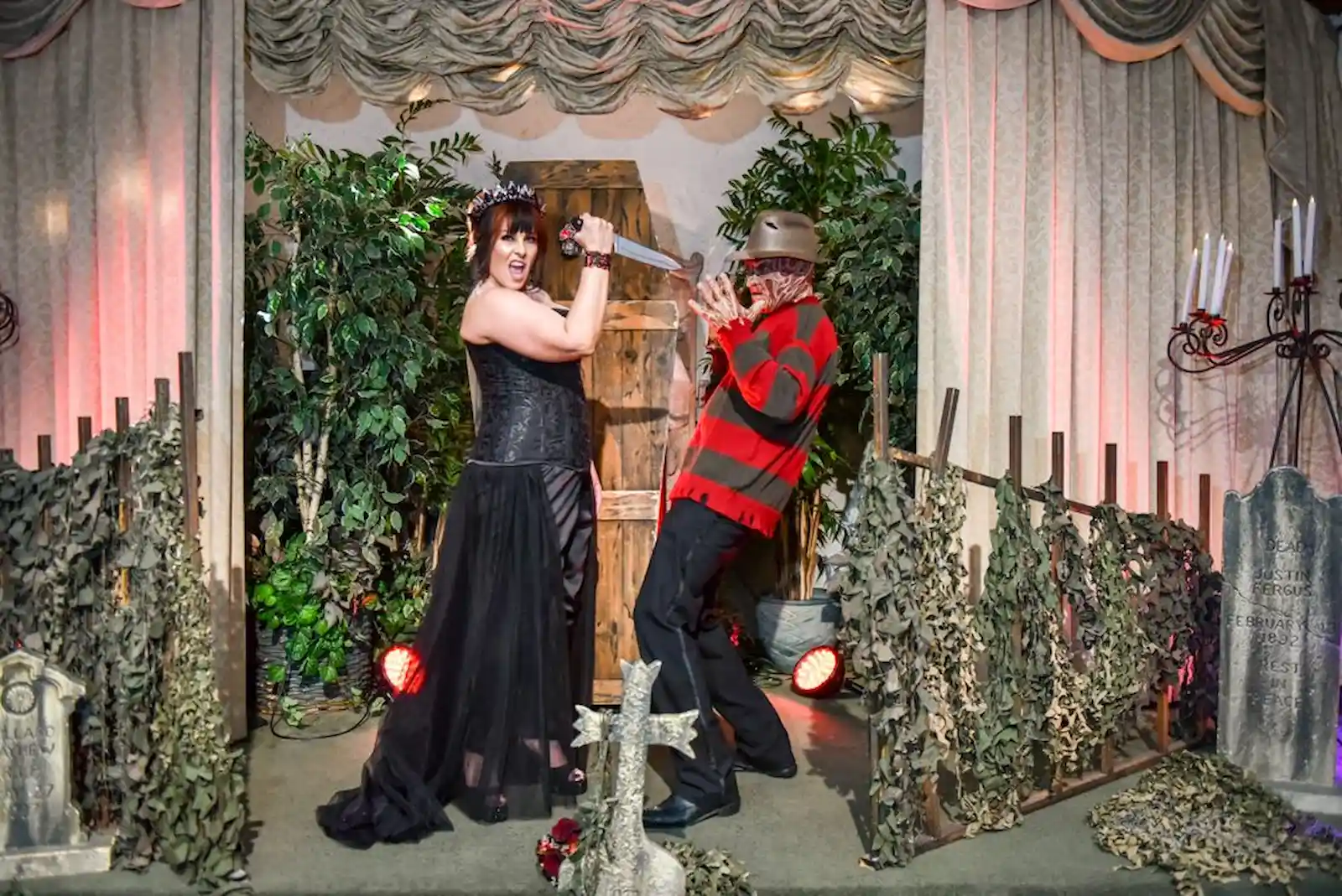 Bride in gothic black gown posing with Freddy Krueger character at a horror-themed Las Vegas wedding chapel with graveyard decor