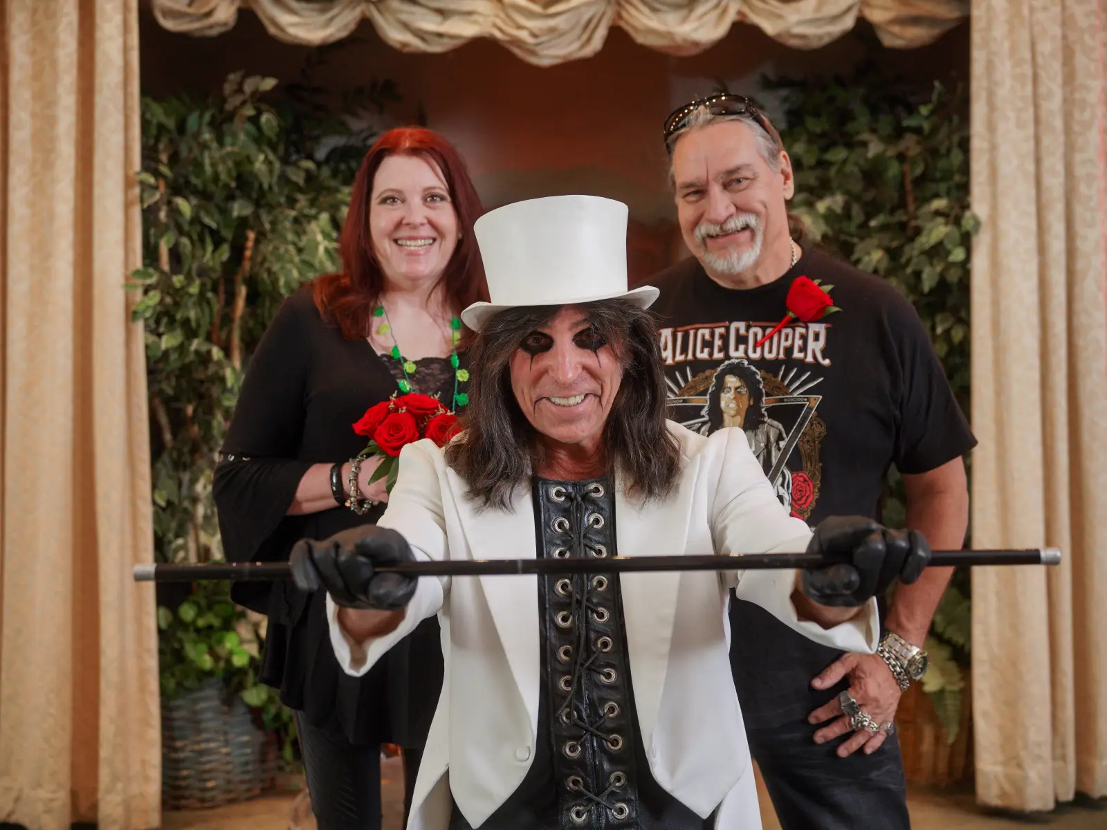 Alice Cooper impersonator officiating a wedding ceremony with the bride and groom standing beside him.