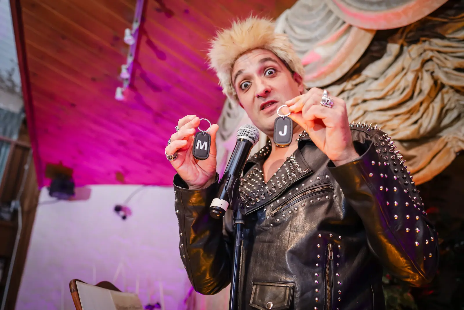 Billy Idol impersonator holding wedding ring keychains during themed ceremony at Viva Las Vegas Wedding Chapel