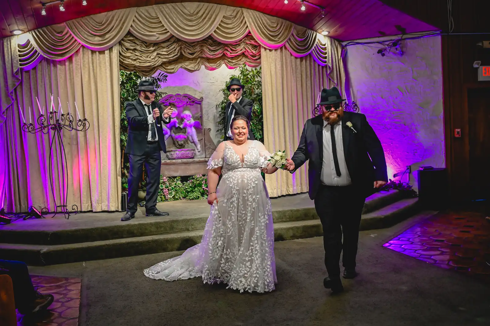 newlyweds walking down aisle Blues Brothers impersonators purple lighting Las Vegas chapel