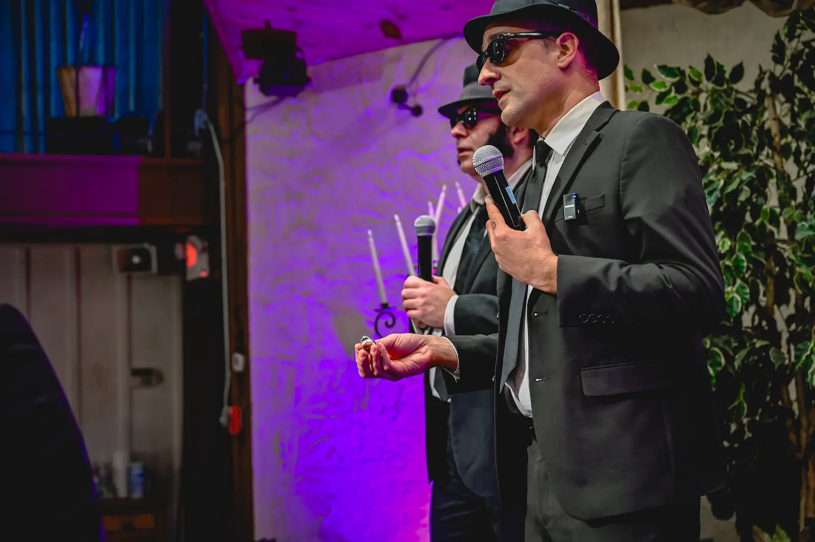 Blues Brothers impersonators holding wedding rings microphone purple lighting Las Vegas