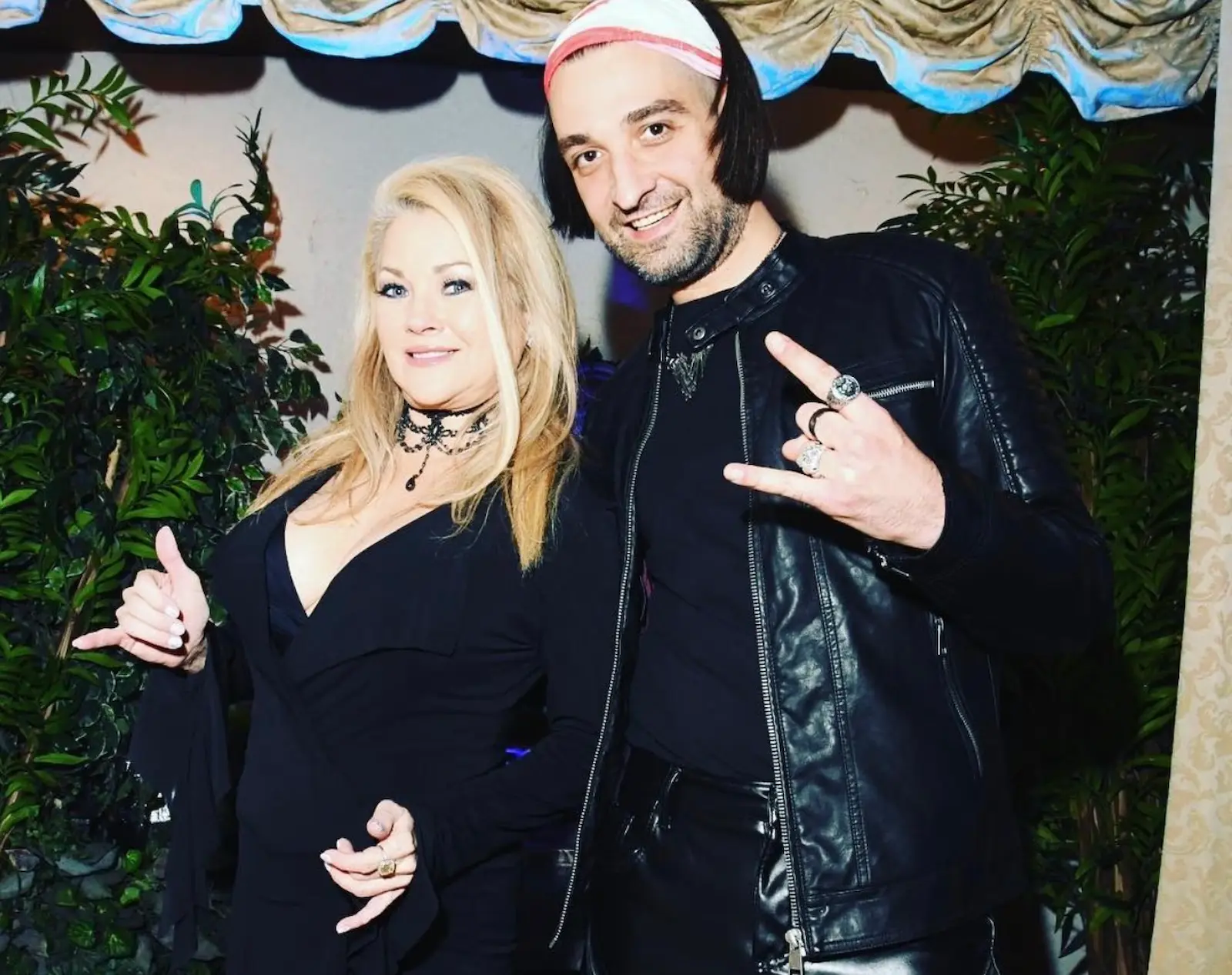 Newlyweds in black posing with Bon Jovi impersonator at rock themed wedding at Viva Las Vegas Wedding Chapel