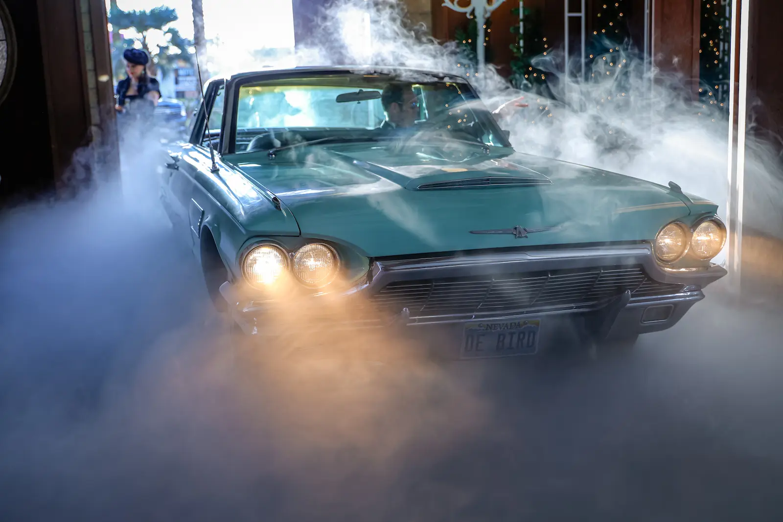 Vintage turquoise Thunderbird rolls through fog during dramatic James Bond themed wedding entrance at Las Vegas chapel