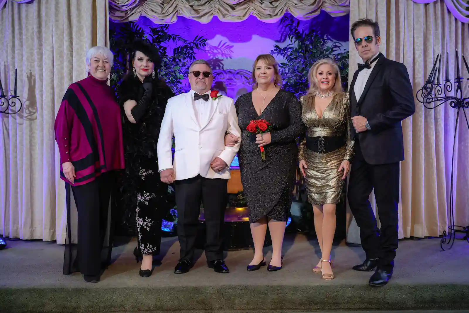James Bond themed wedding group photo with newlyweds and guests in glamorous black and gold formal attire at Las Vegas chapel