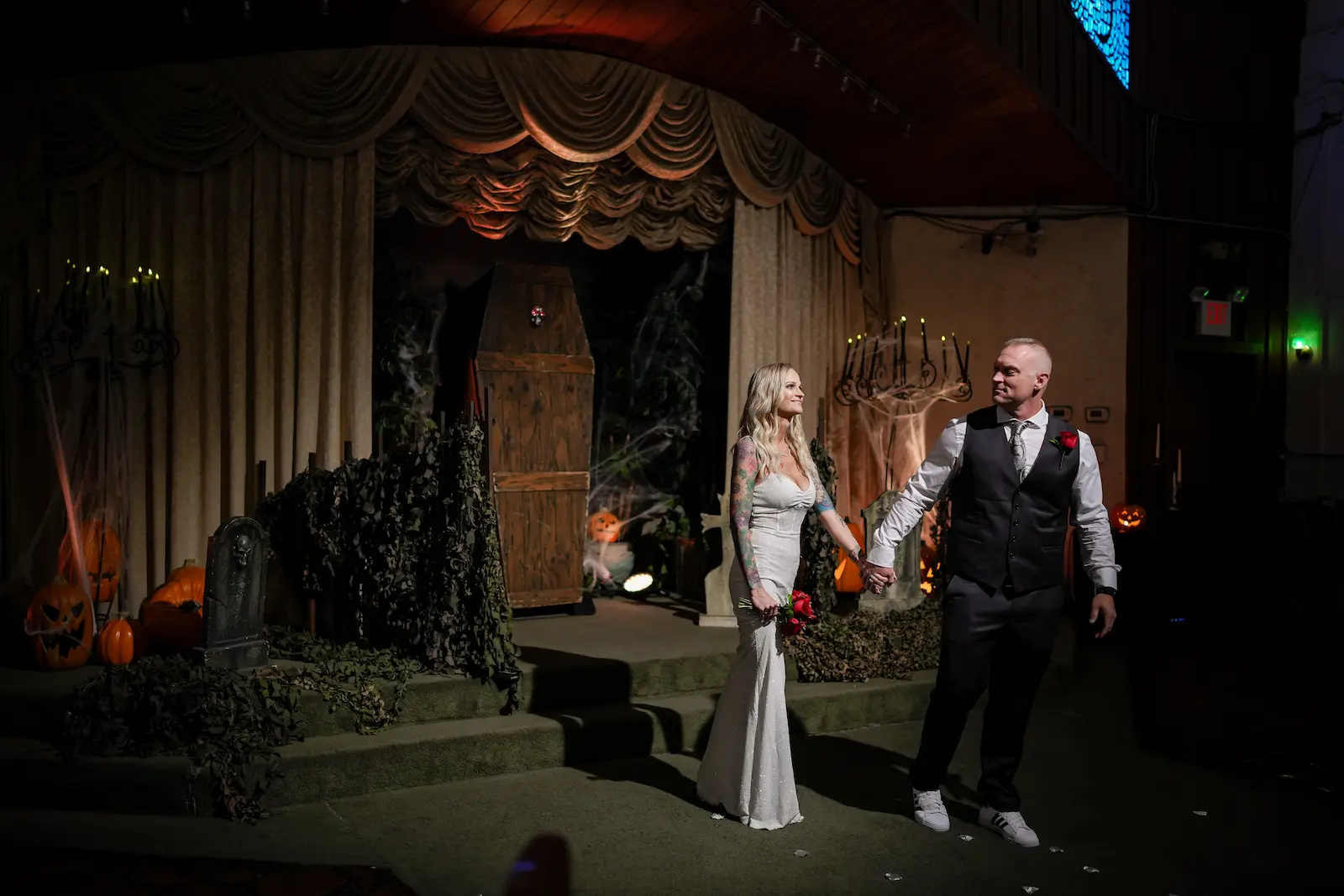 Couple holding hands in front of a halloween wedding altar with pumpkins and coffin decor at a Las Vegas chapel.