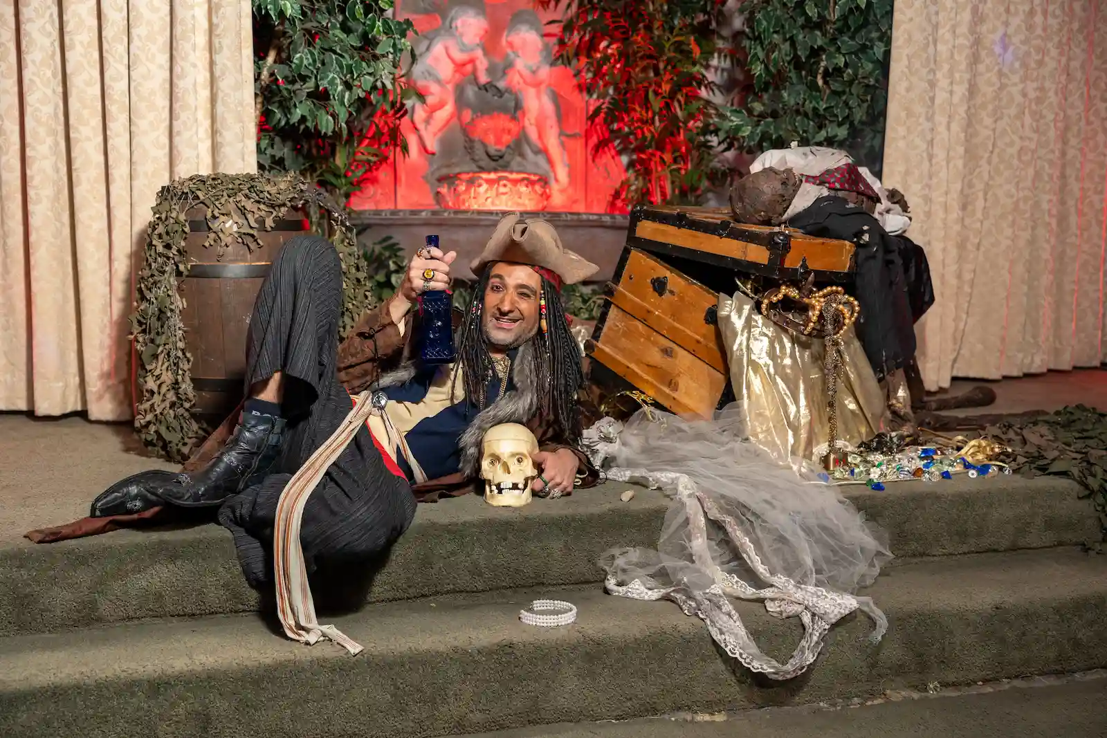 Pirate character holding a bottle beside a treasure chest and skull prop at a Las Vegas themed wedding venue.