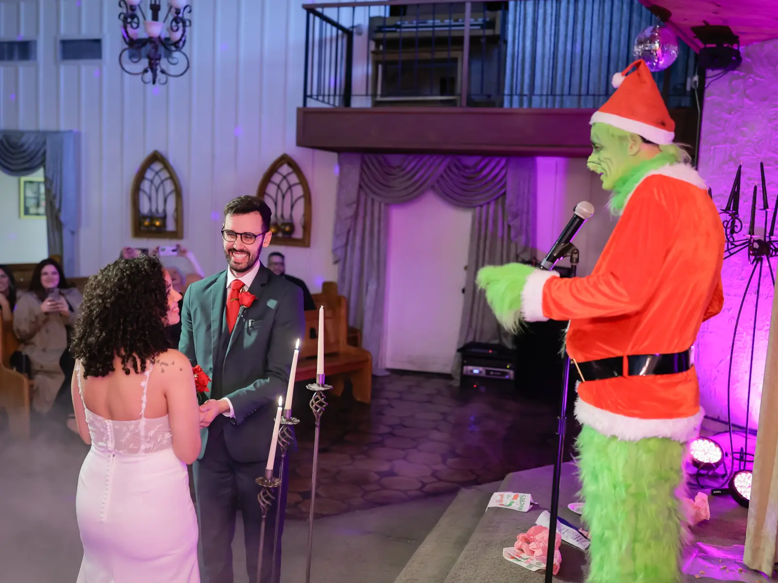 Couple holding hands with Grinch officiant at wedding ceremony.