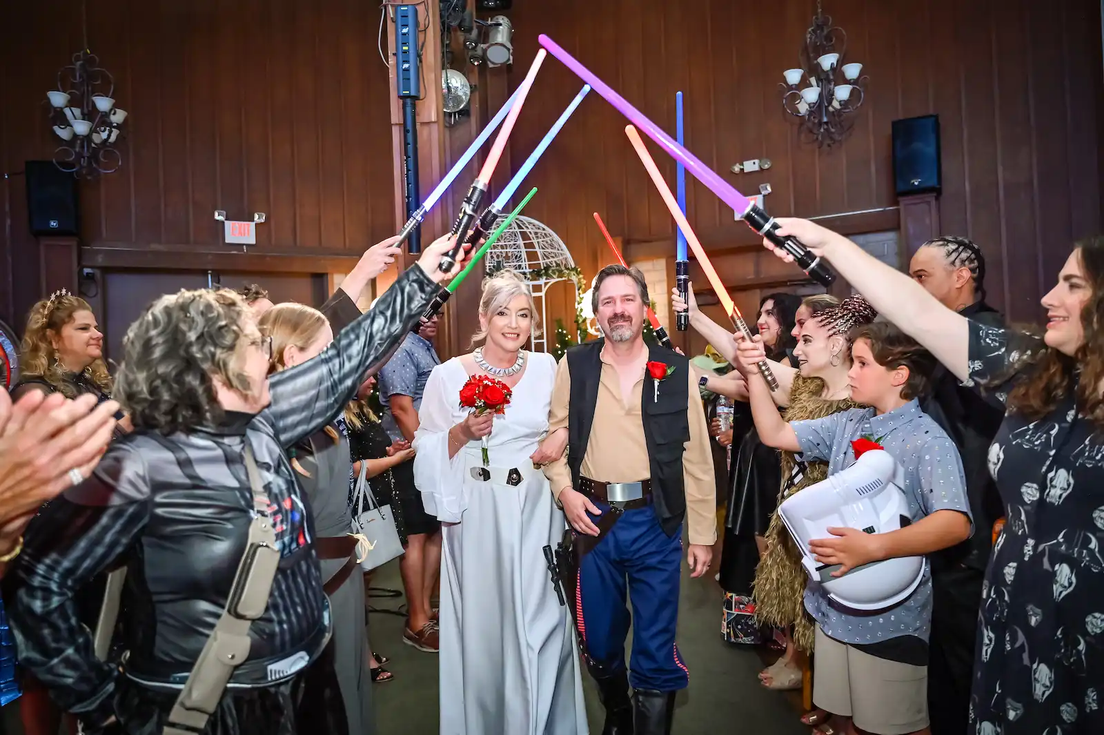 Star Wars-themed couple walking through a lightsaber arch held by guests at a Las Vegas wedding recessional.