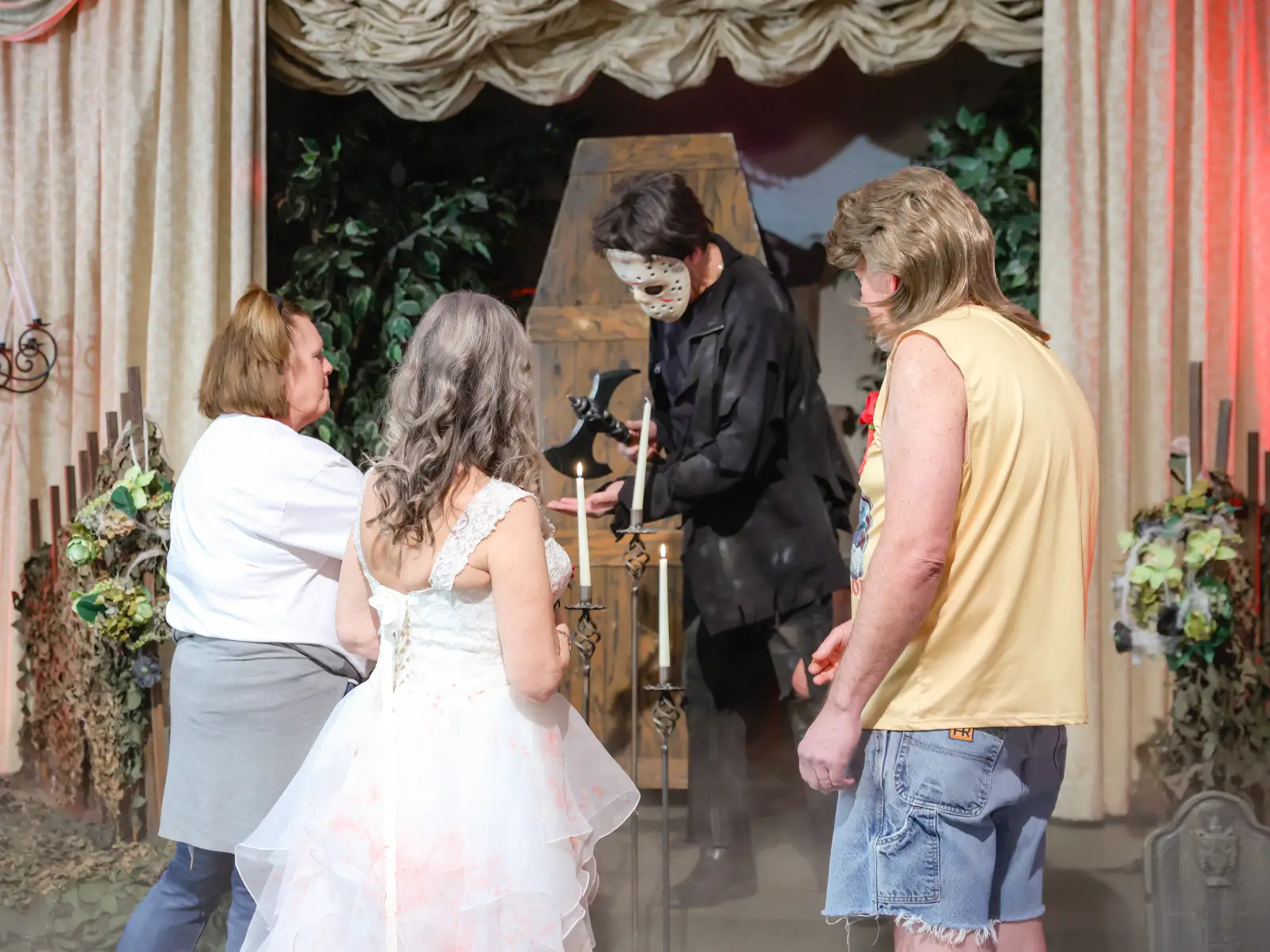 Couple at a horror-themed Las Vegas wedding ceremony with a masked officiant, candles, fog, and gothic decor.