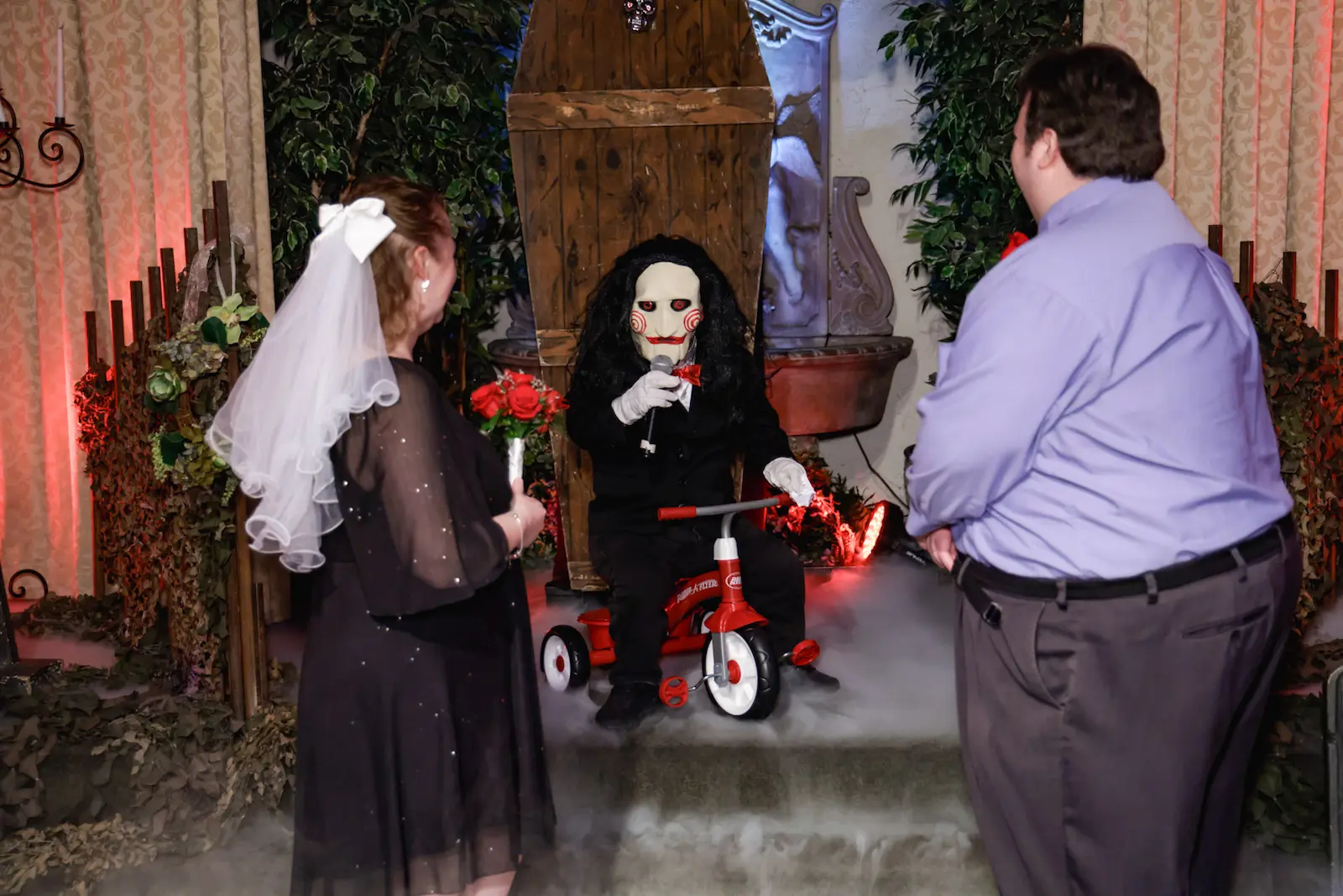 Couple exchanging vows with Saw Billy puppet officiant during horror themed wedding at Viva Las Vegas Wedding Chapel