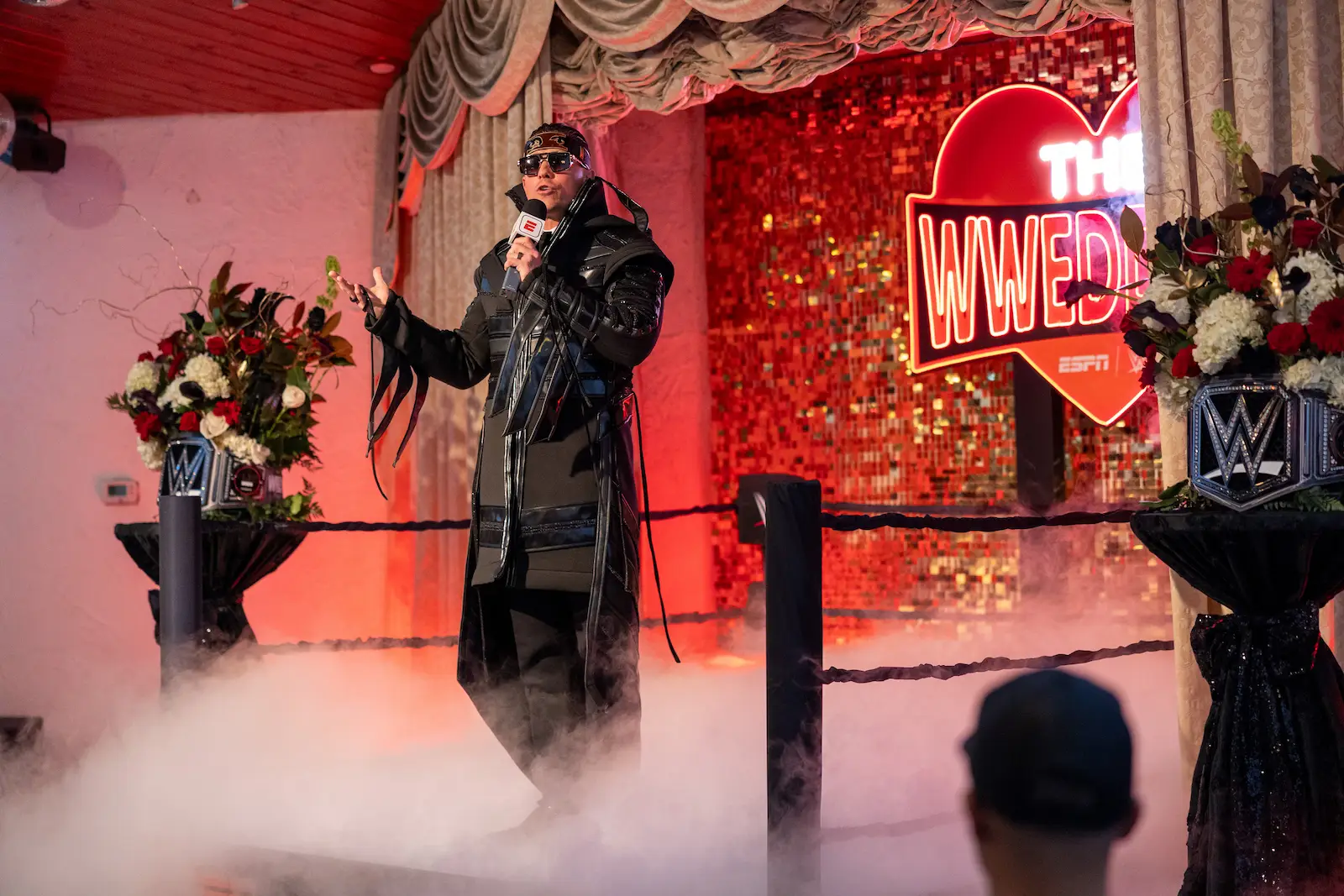 WWE wrestler officiant with microphone and fog at The WWedding ESPN event at a Las Vegas wedding chapel