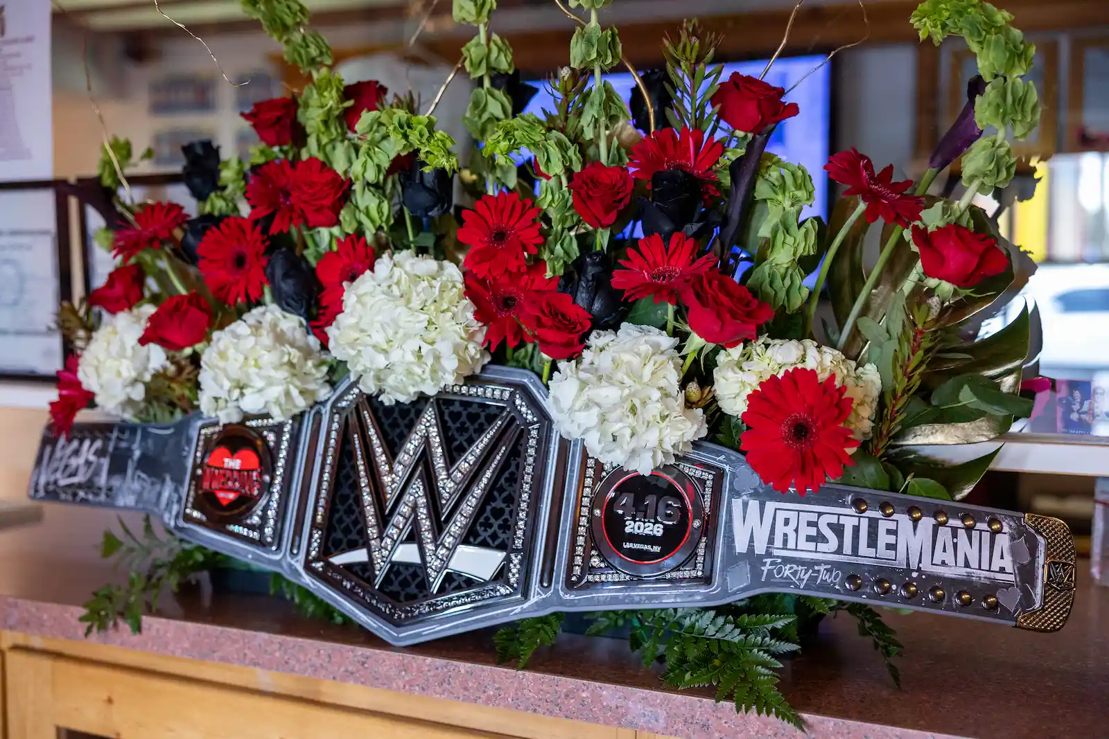 WWE WrestleMania 42 championship belt decorated with red and white floral arrangement at a Las Vegas wedding
