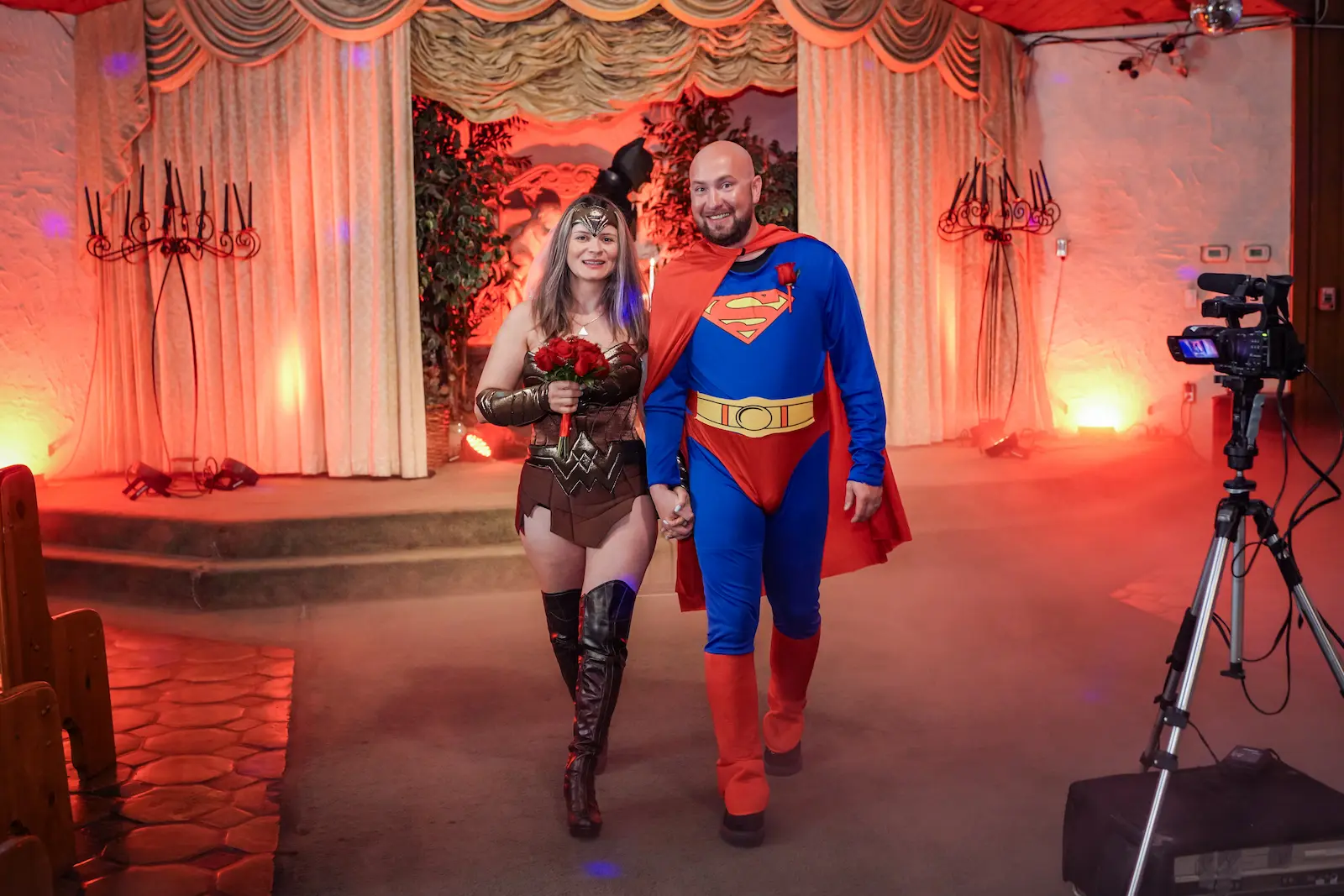 Newlyweds in Wonder Woman and Superman costumes walk hand in hand down the aisle after superhero themed wedding ceremony at Las Vegas chapel