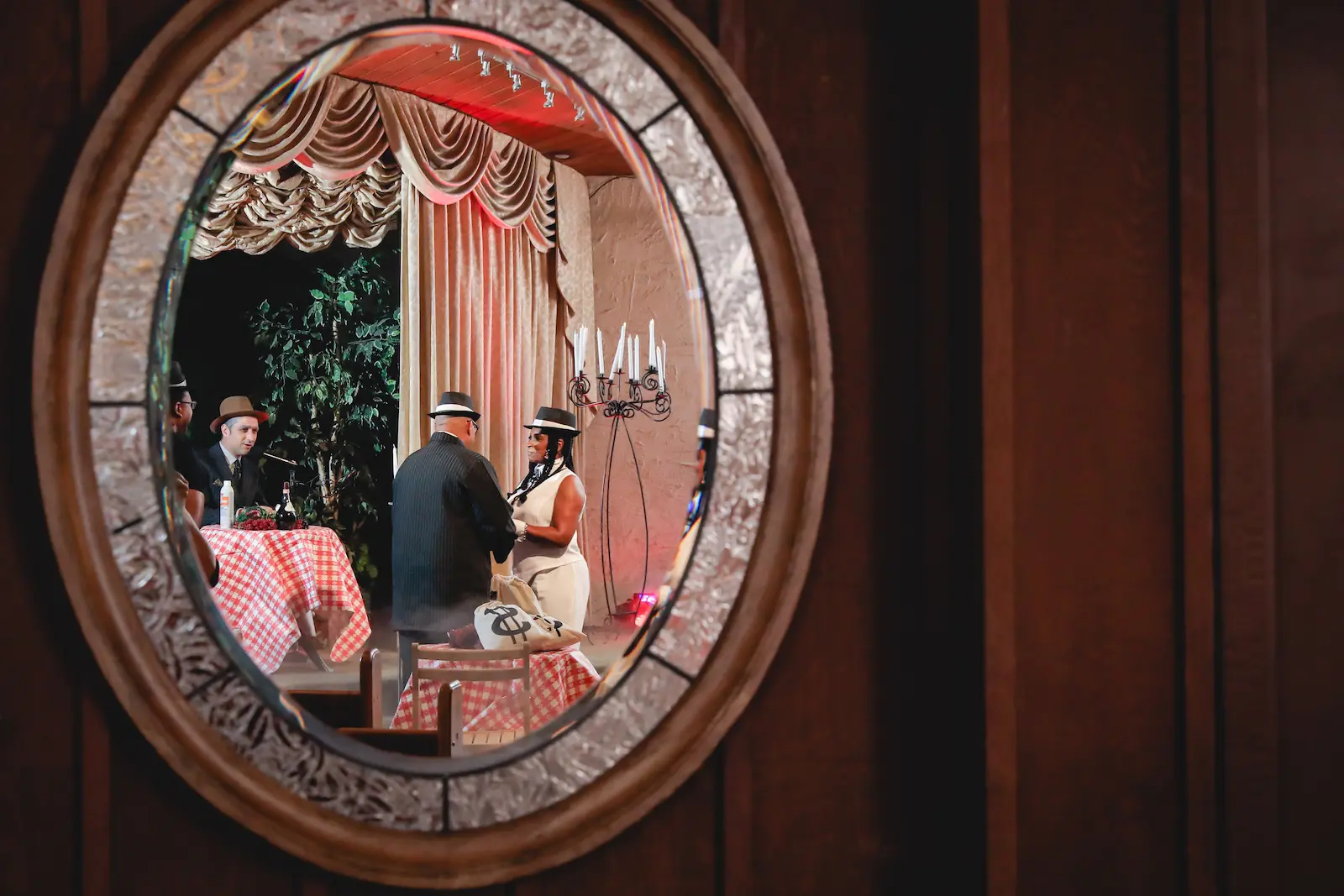 Gangster themed wedding ceremony reflected in ornate oval mirror at Las Vegas chapel