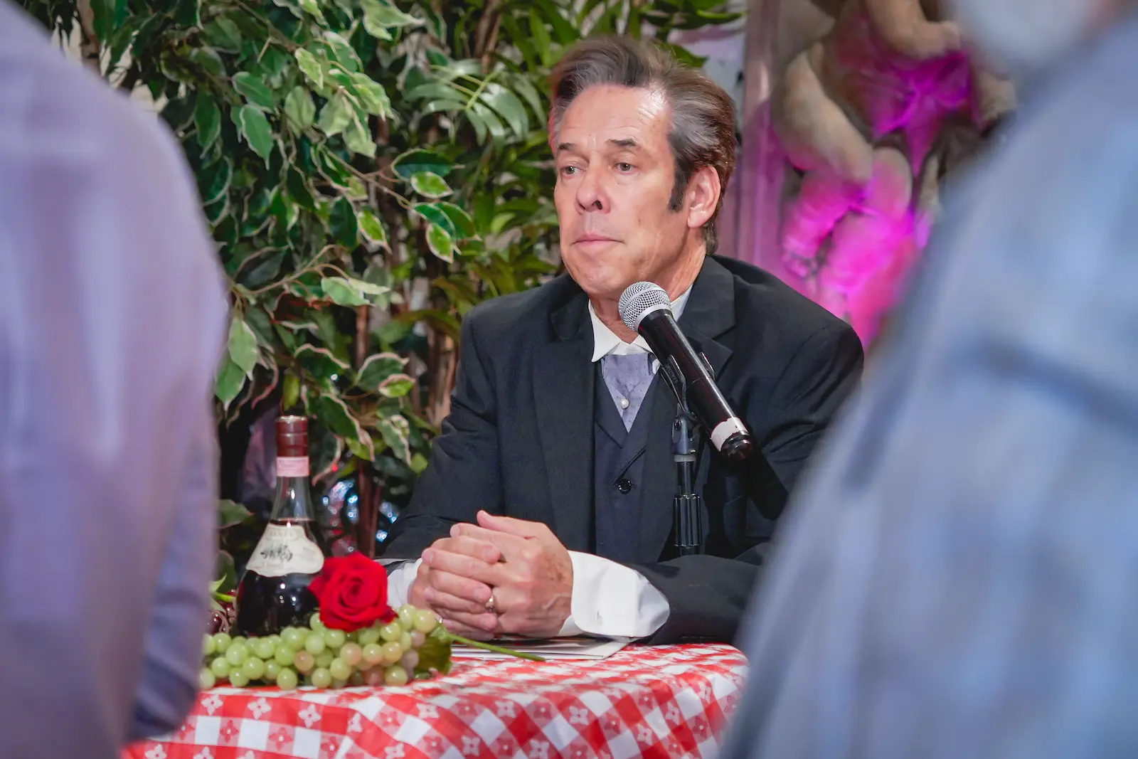 Godfather impersonator seated at microphone with wine and roses officiates wedding at Las Vegas chapel