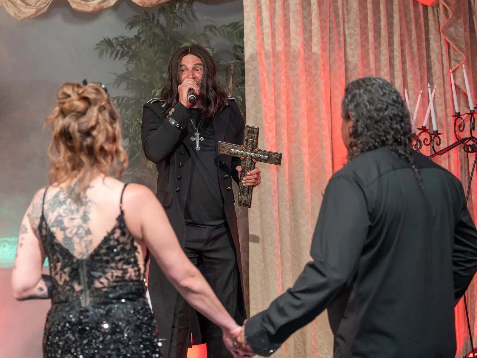 Ozzy Osbourne impersonator officiating a gothic wedding ceremony holding a cross at a Las Vegas wedding chapel