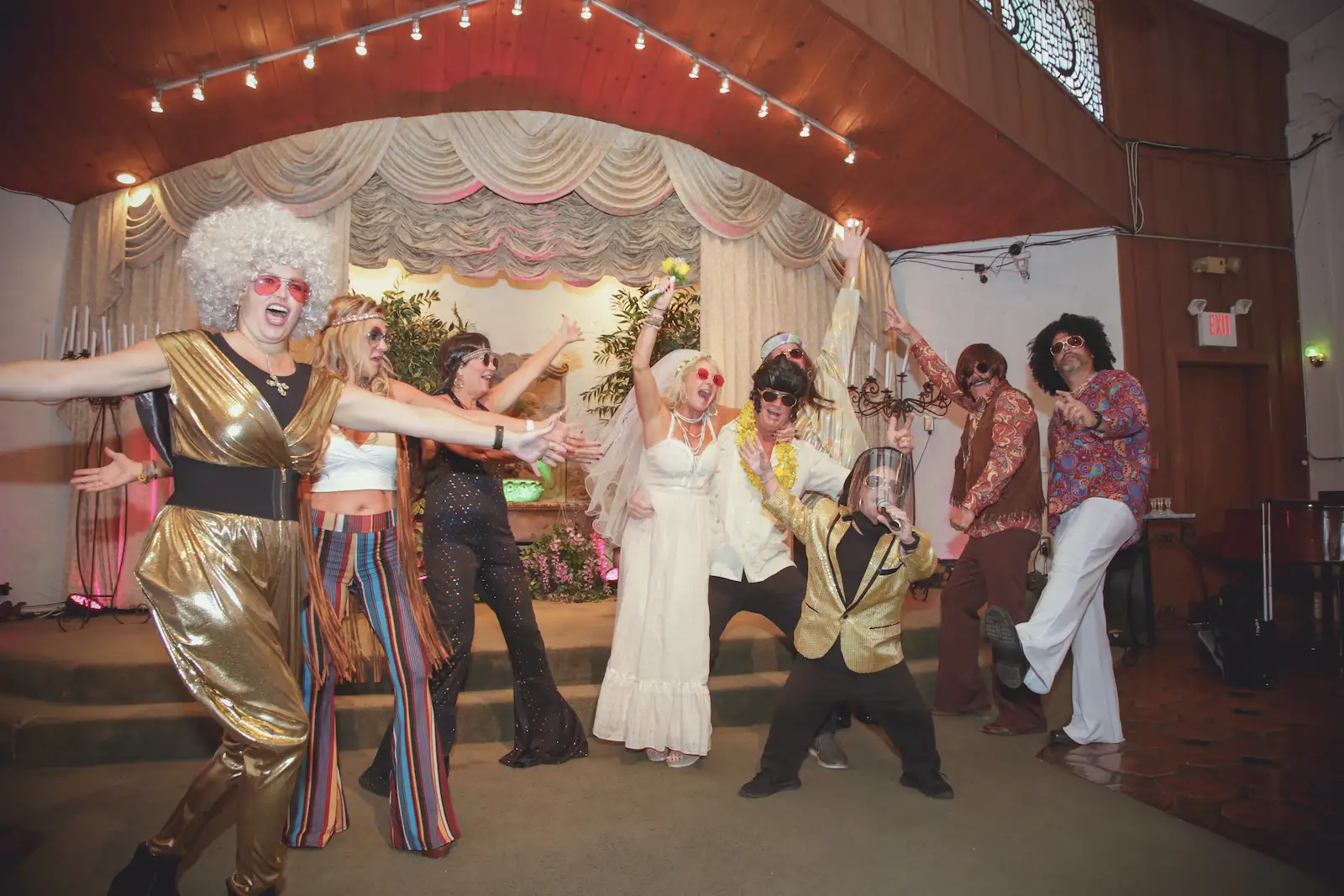Bride and disco hippie wedding party dance together in colorful 70s outfits at Las Vegas chapel