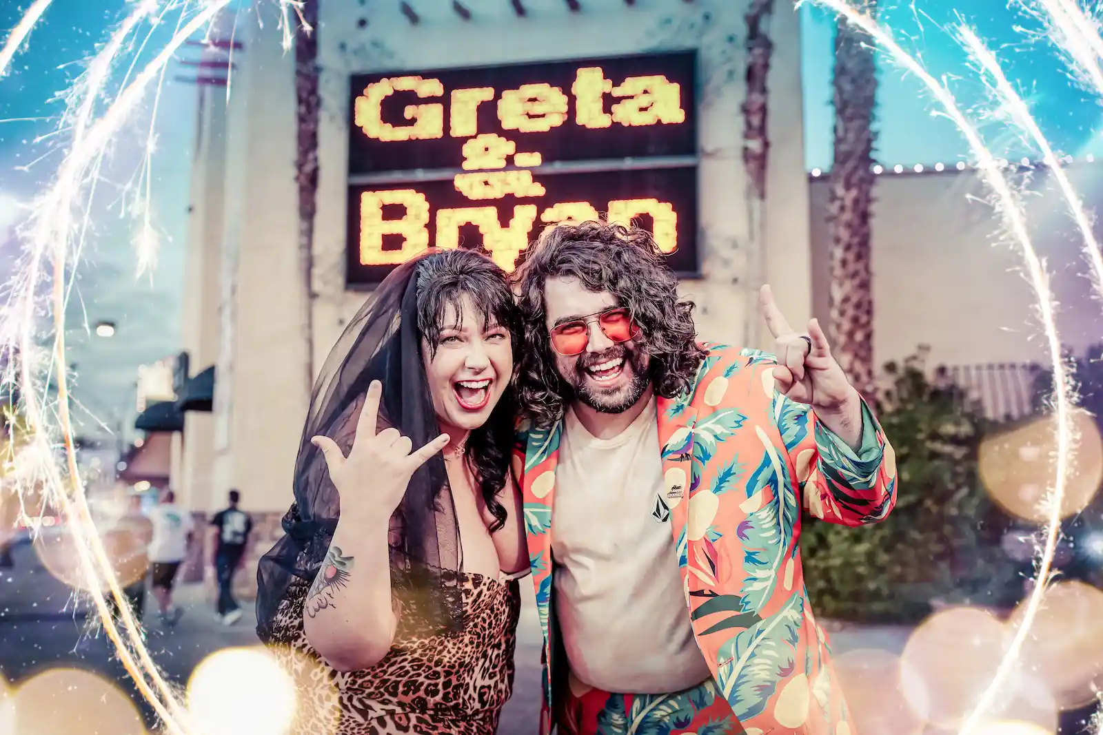 Newlyweds celebrate with sparklers in front of personalized marquee sign outside Las Vegas wedding chapel