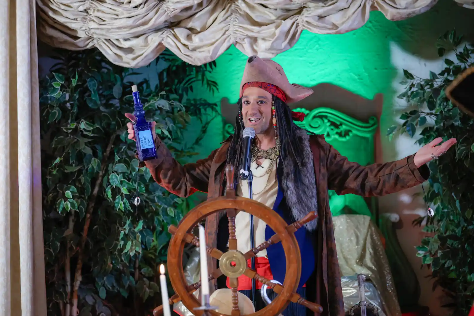 Pirate officiant toasting the bride with a blue bottle during a Las Vegas pirate-themed wedding ceremony.