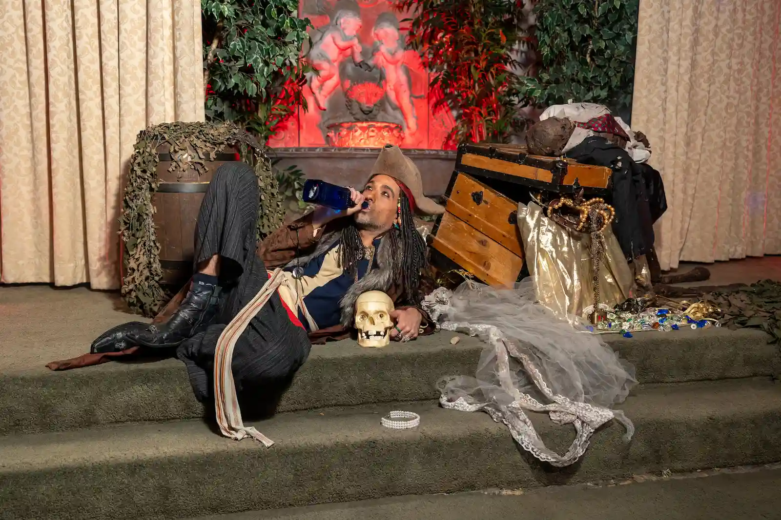 Pirate character lounging on chapel steps with a blue bottle, skull prop, and open treasure chest at a Las Vegas wedding venue.
