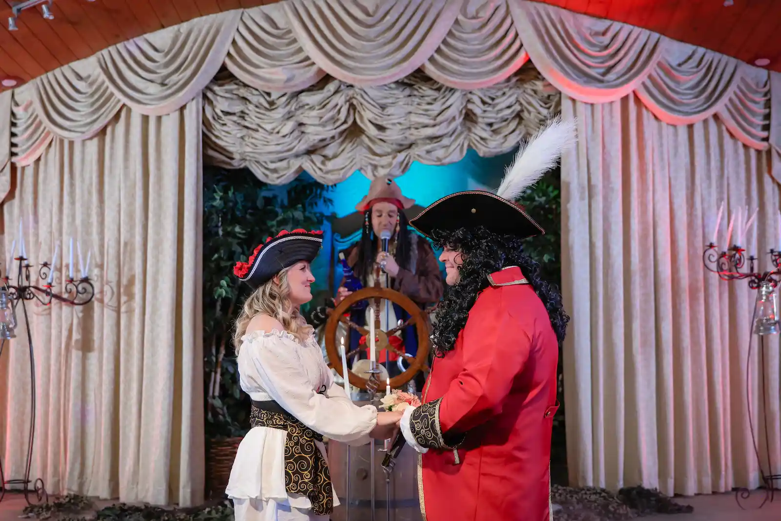 Couple in full pirate costumes exchanging vows before a pirate officiant at a Las Vegas wedding chapel.
