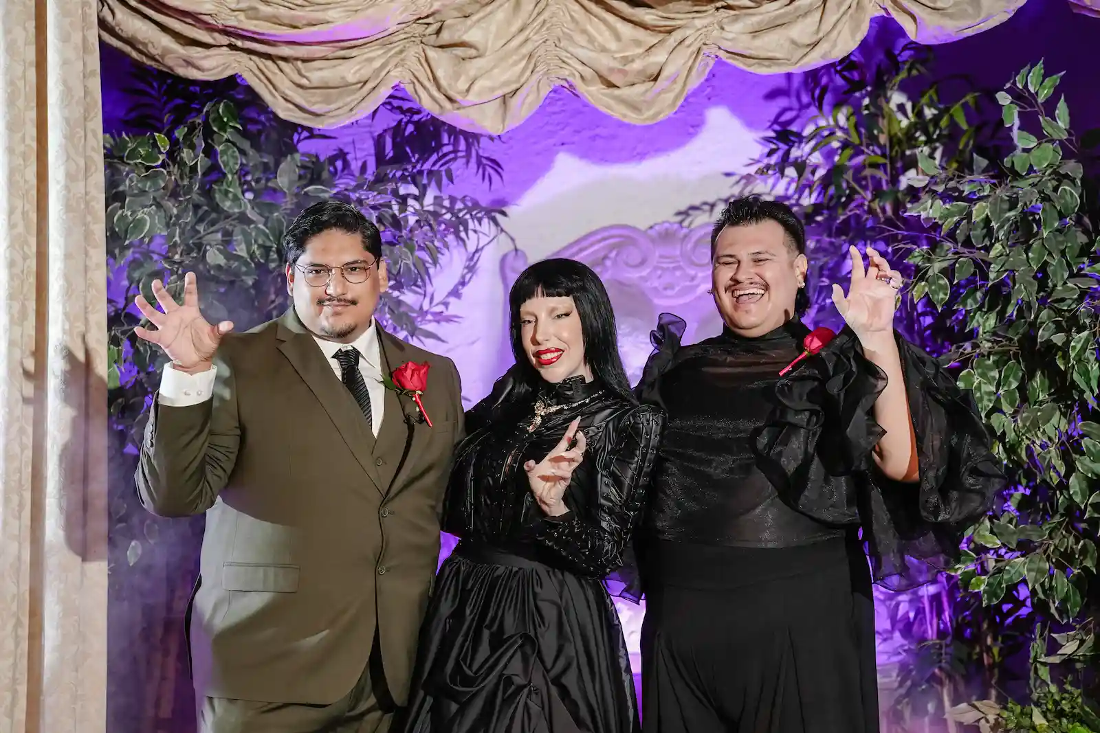 Newlyweds pose with Lady Gaga impersonator in black dress under purple lighting at Las Vegas wedding chapel