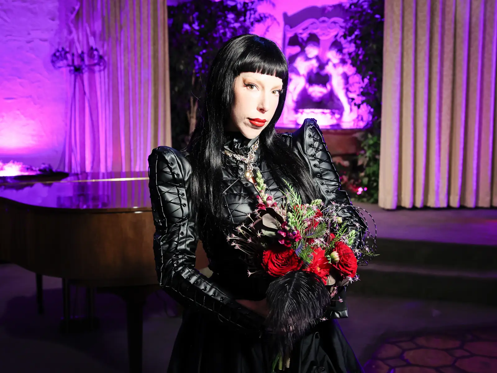 gothic bride in black dress holding red bouquet during alternative wedding photoshoot