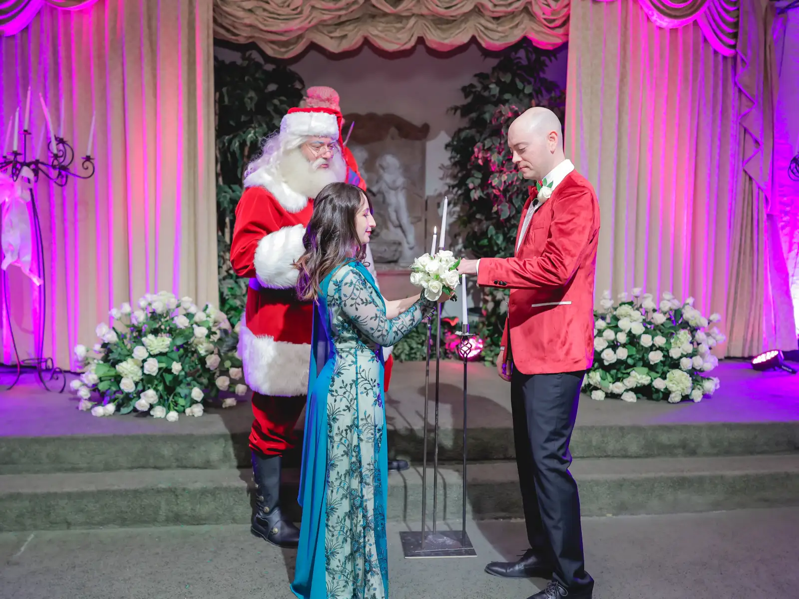 Couple holding wedding unity candle with Santa Claus