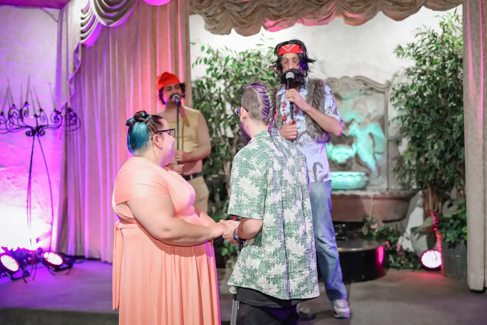 Bride and groom hold hands during vows as Cheech and Chong impersonators officiate their Las Vegas wedding