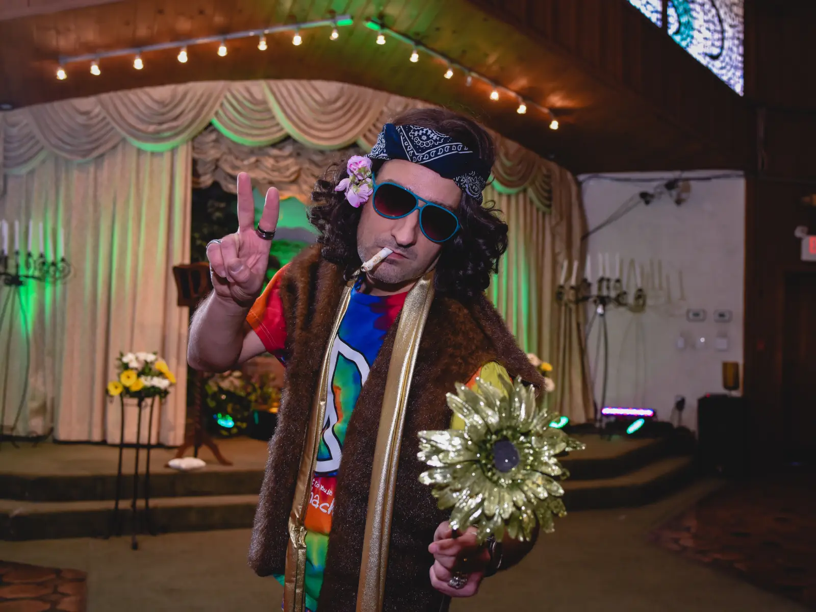 hippie wedding performer giving peace sign with sunglasses at themed las vegas wedding