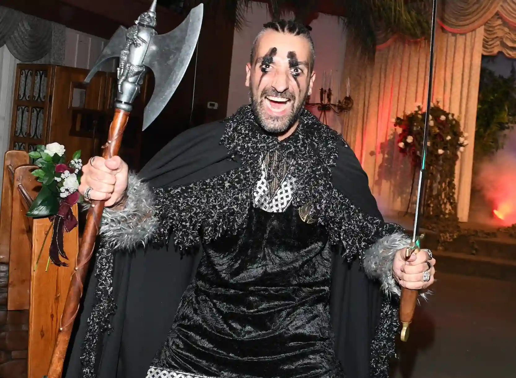 Viking warrior officiant in black cape and face paint wields battle axe and sword at Las Vegas wedding chapel