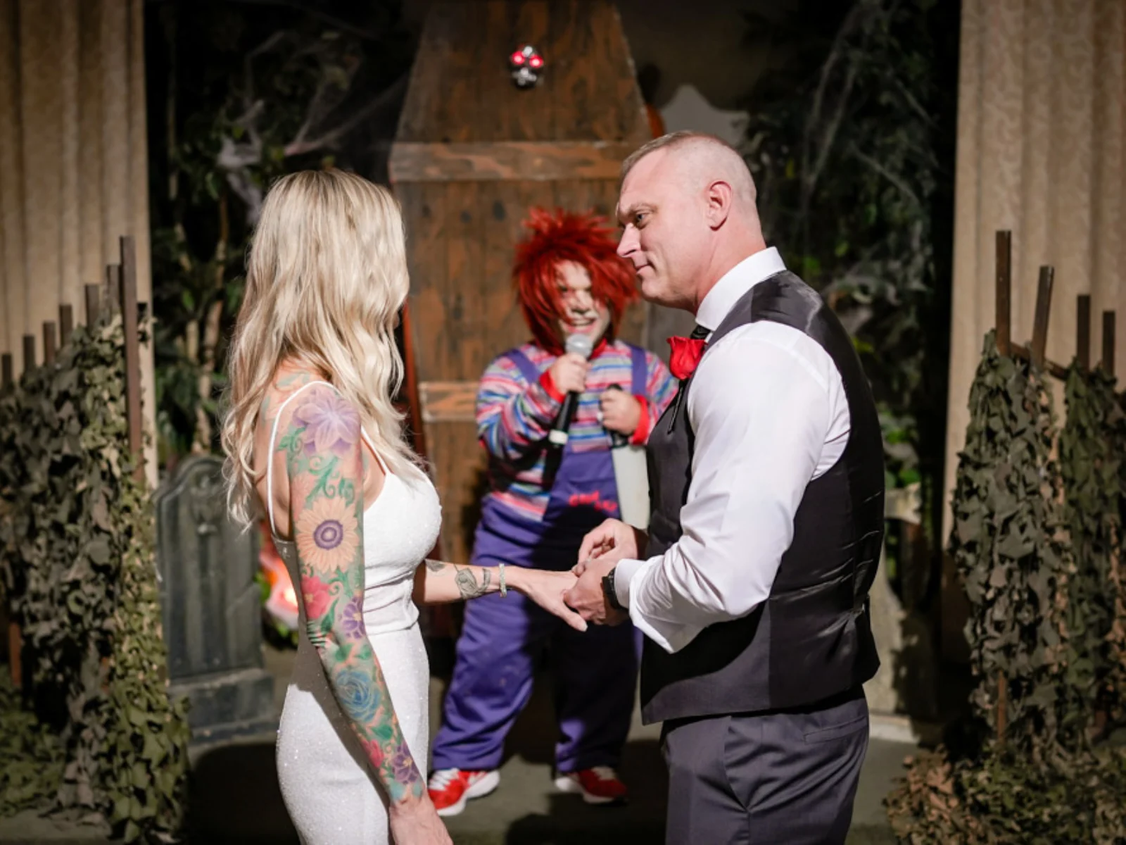 Chucky impersonator in striped shirt and overalls officiating wedding ceremony as couple exchanges rings at Las Vegas horror themed wedding