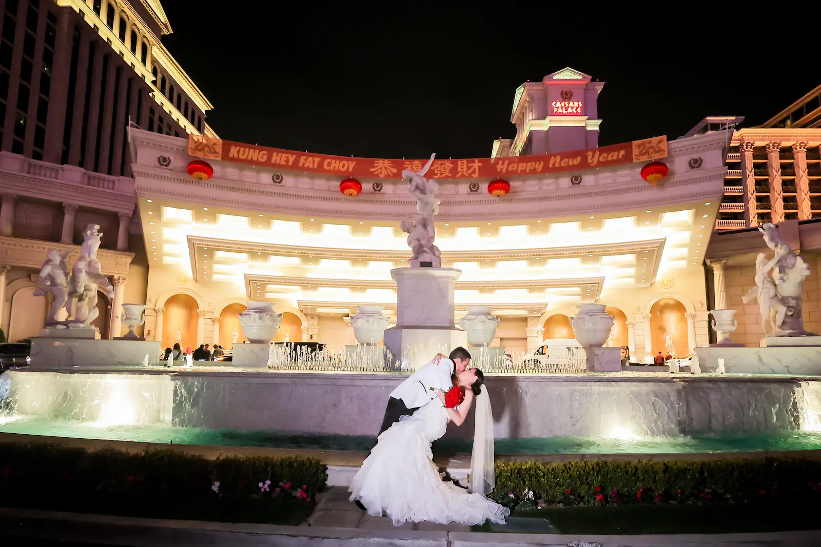 Groom dipping his wife in front of the Caesars Palace at their wedding in Vegas