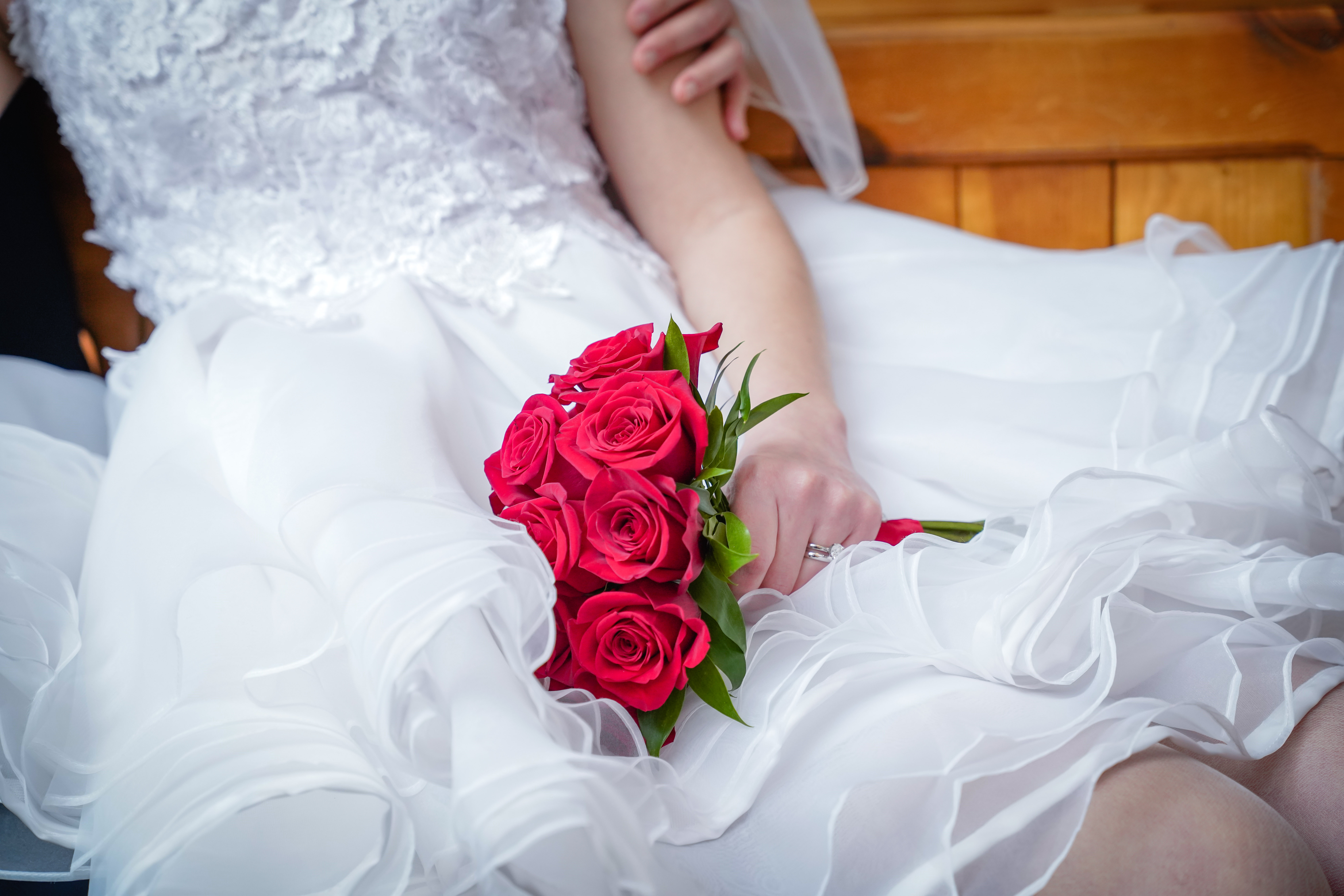 Bride holding bouquet of red roses on white wedding dress during intimate Las Vegas ceremony moment.