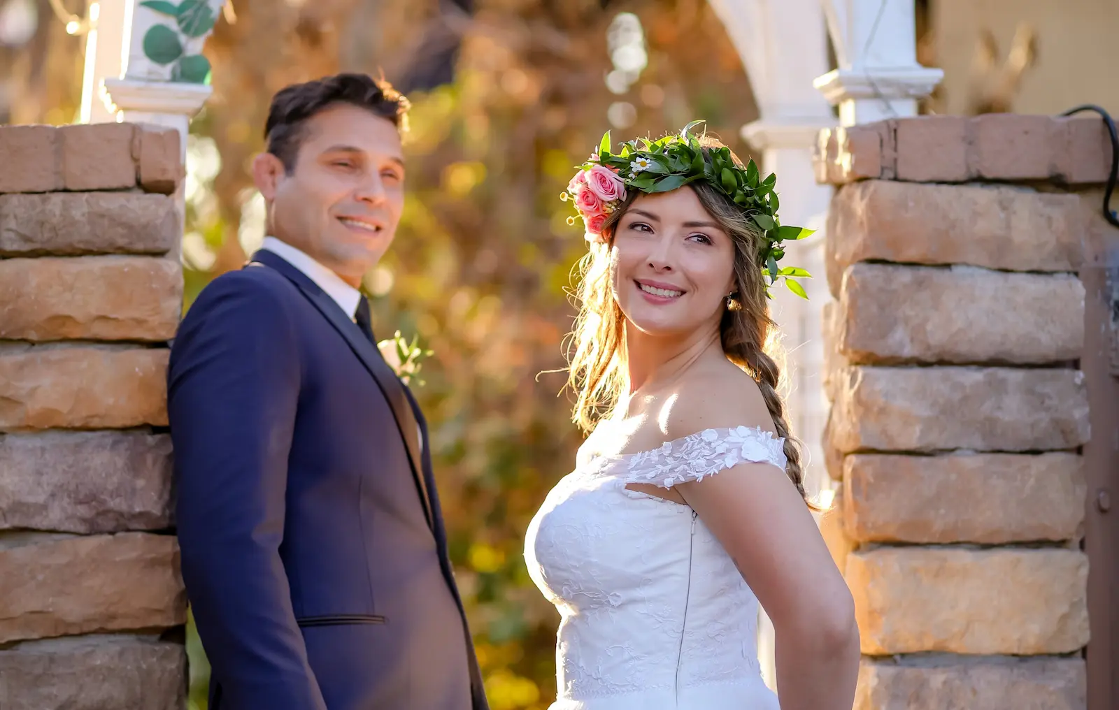 Bride wearing floral crown smiling at groom during golden hour garden wedding ceremony