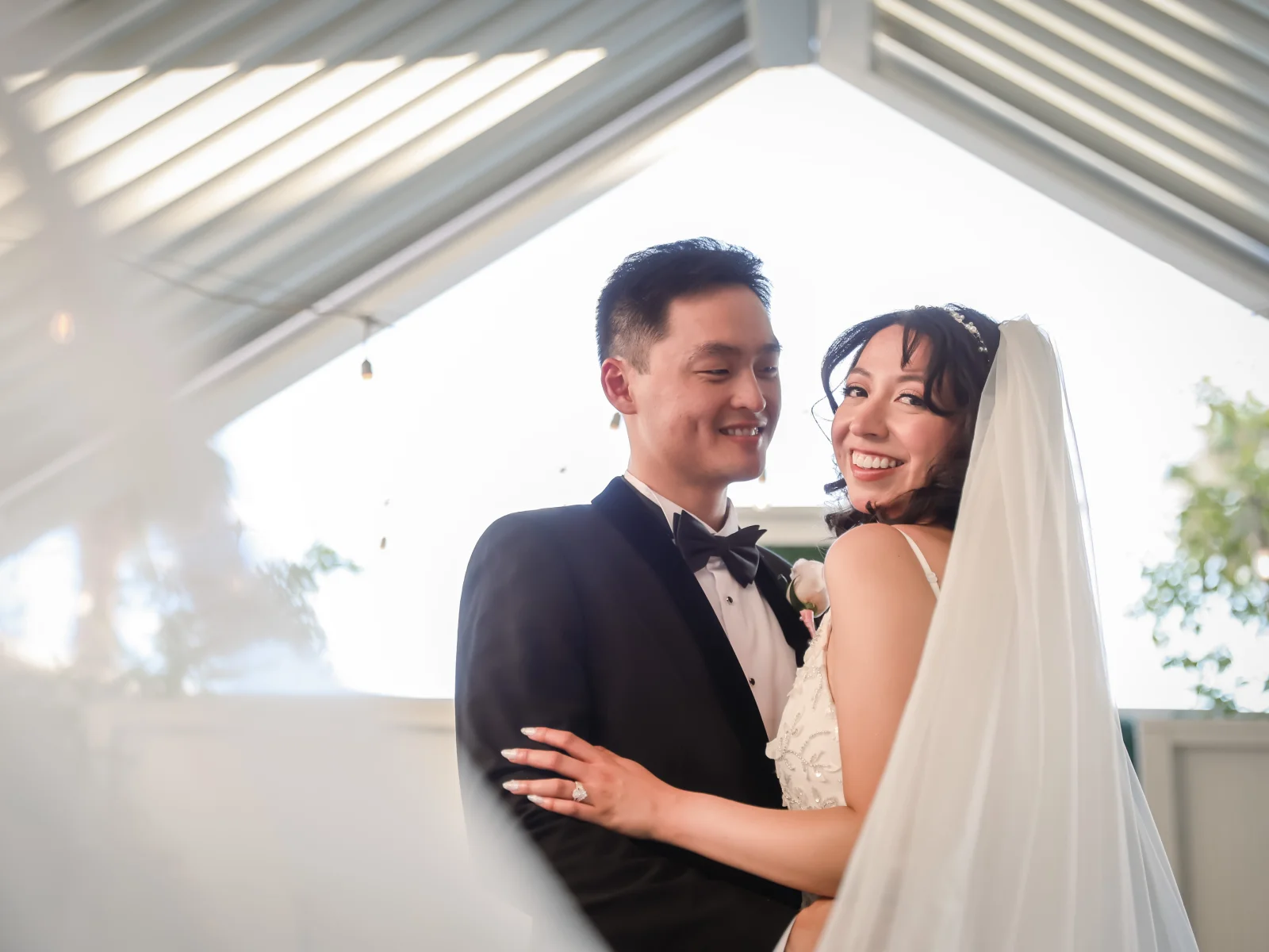 Smiling bride and groom embracing under the covered outdoor ceremony space at Viva Las Vegas Wedding Chapel.