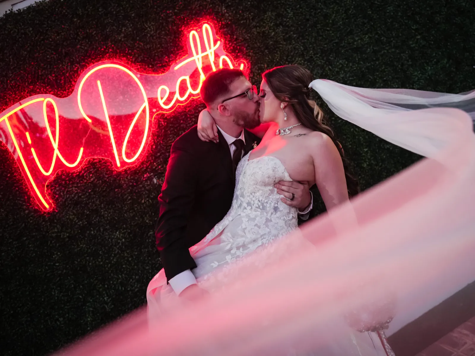 A couple kisses under a glowing red "