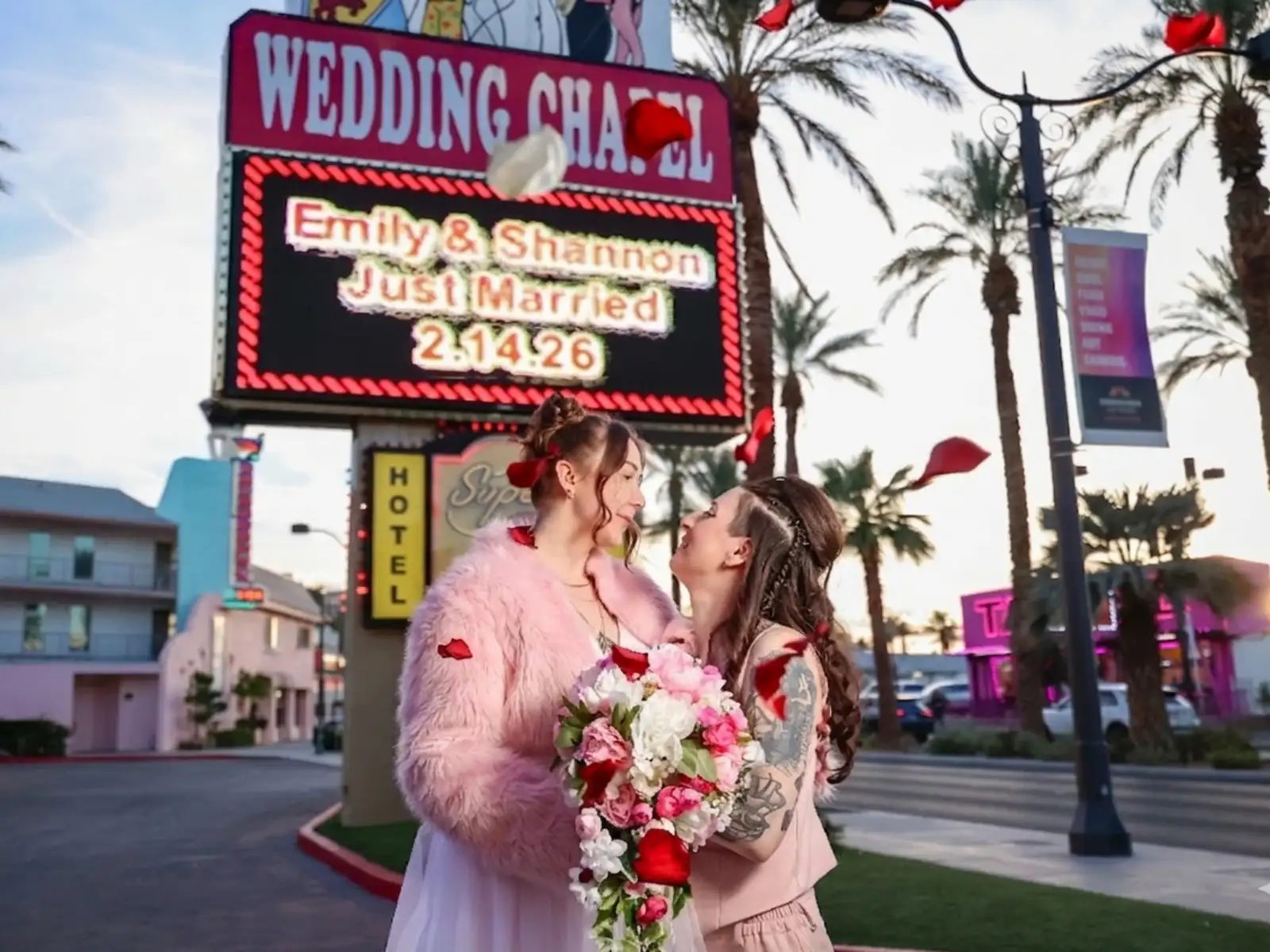 A couple poses in front of a Vegas wedding chapel sign that reads "Just Married".