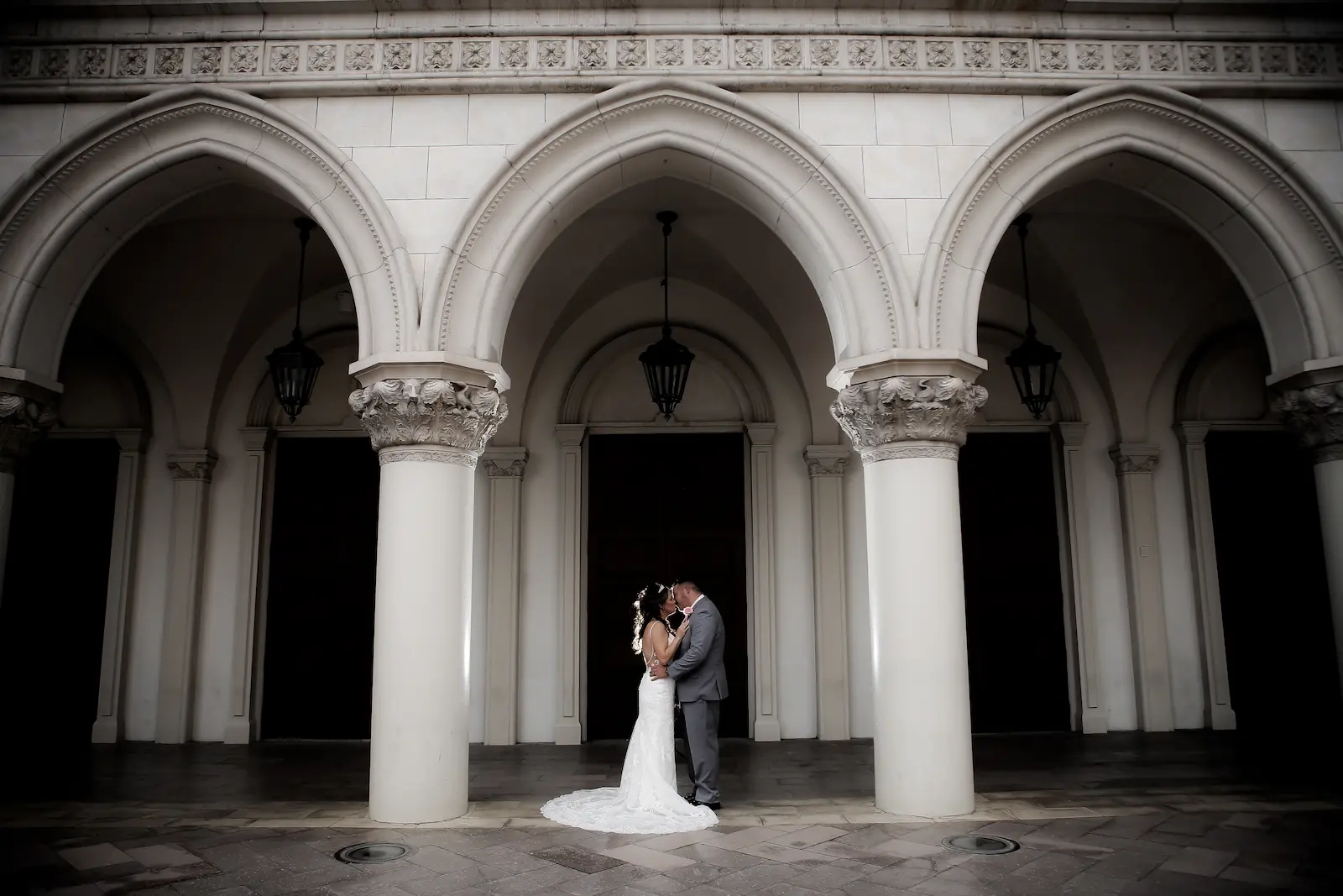 Bride and groom sharing a kiss under grand white arched columns on the Las Vegas Strip.