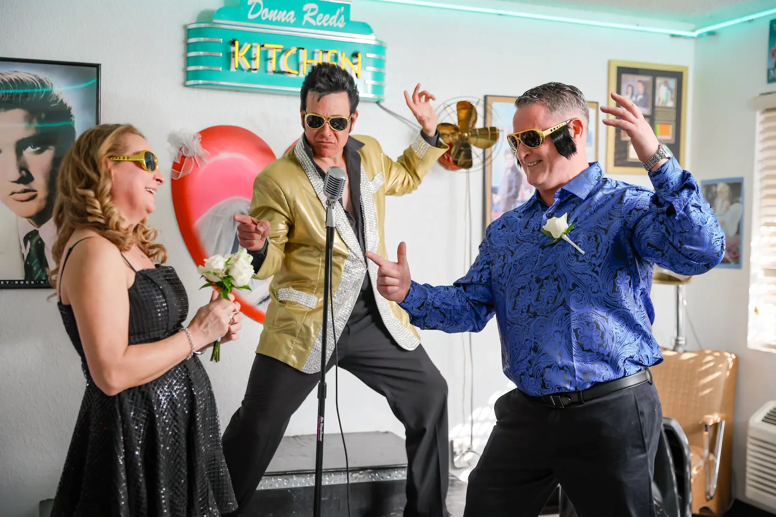 Elvis impersonator performs as a couple dances in matching gold sunglasses at a Vegas retro chapel