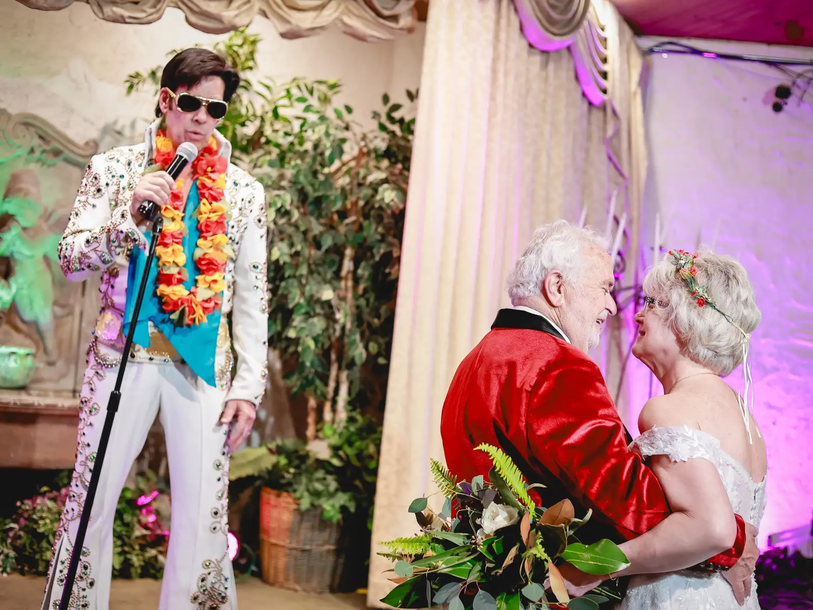 Romantic Las Vegas Elvis wedding dance with senior bride and groom embracing in chapel while Elvis impersonator sings live during elegant ceremony