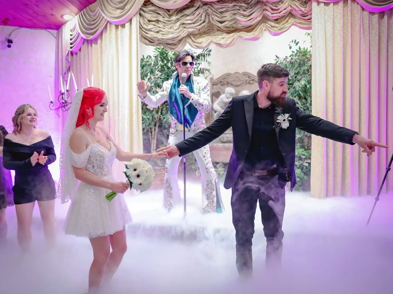 Fun Las Vegas Elvis wedding ceremony with bride and groom dancing in romantic chapel fog while Elvis impersonator performs live on stage