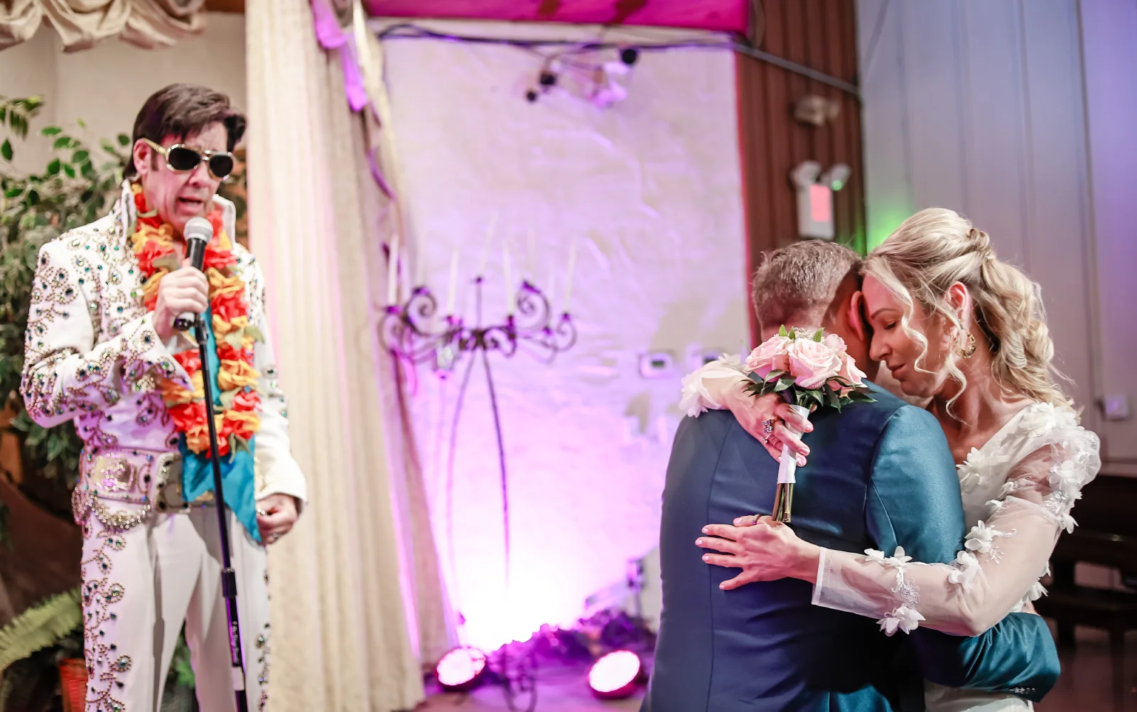 Romantic Las Vegas Elvis wedding first dance with bride and groom embracing closely in elegant chapel while Elvis impersonator sings live during ceremony