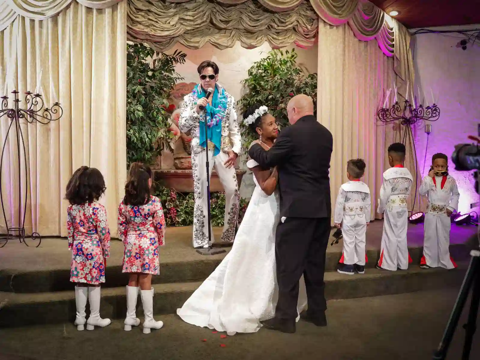 Family wedding ceremony at a Las Vegas chapel with Elvis officiant and children dressed in matching outfits including mini Elvis suits