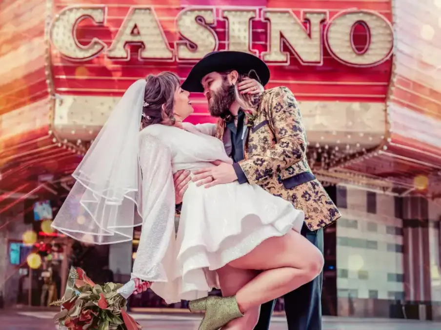 Bride and groom in romantic dip pose in front of neon casino sign on Fremont Street Las Vegas