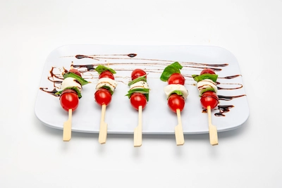Caprese skewers with tomato, mozzarella, and basil drizzled with balsamic glaze