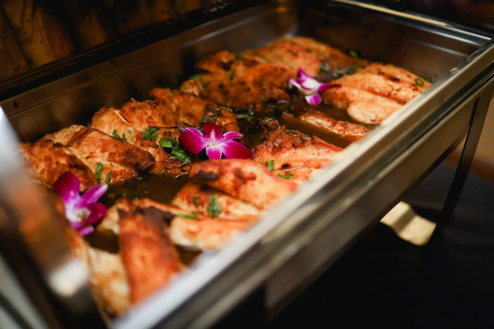 Chicken marsala garnished with orchids served from a chafing dish at a Las Vegas wedding reception