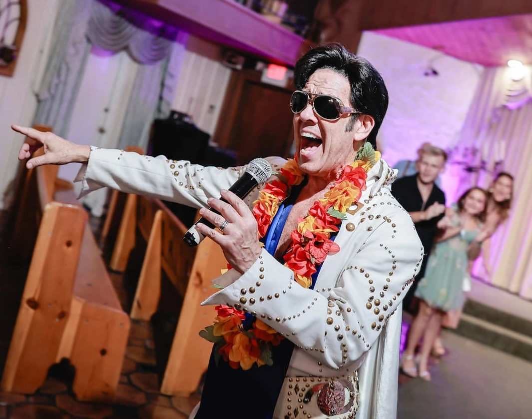 Elvis impersonator in a white studded jumpsuit and colorful lei performs at a Vegas wedding chapel