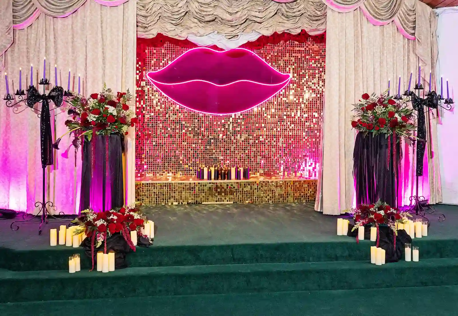 Full gothic wedding decor setup with neon lips sign, red rose floral arrangements, black candelabras, and candles at Viva Las Vegas Weddings chapel