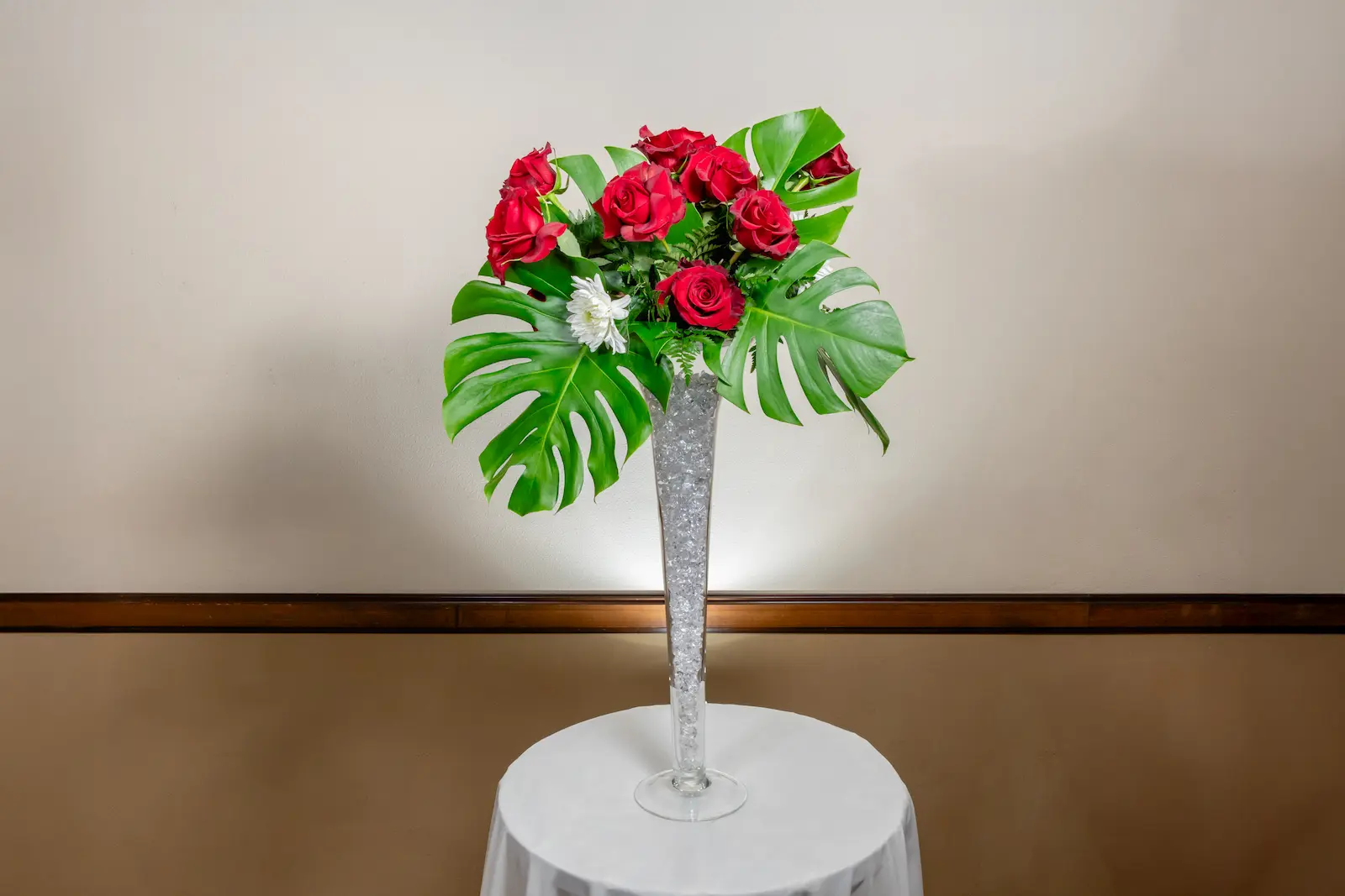 Tall red rose reception centerpiece with tropical monstera leaves in a crystal-filled trumpet vase at Viva Las Vegas Weddings